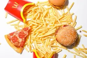 A spread of fast food including fries, pizza, and a burger, raising the question, how much is a Big Mac in Denmark, in the context of local fast food prices.