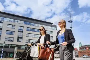 Two women with bicycles walking in city